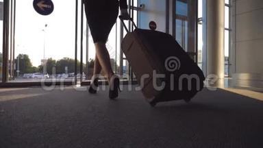 商务女士带着行李通过自动玻璃门离<strong>开机</strong>场。 从终点站走出来的年轻女子